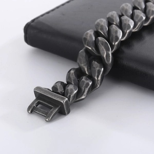 Close-up of vintage silver Cuban link bracelet with hammered texture on black leather