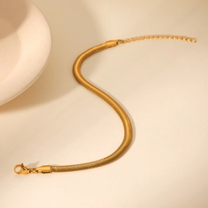Detail of adjustable 18k gold snake chain bracelet with lobster clasp on beige background