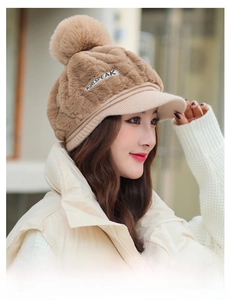 Detail of khaki plush winter hat featuring quilted texture, fluffy pompom and visor