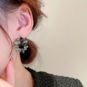 Macro detail of vintage floral earring with black and clear crystals on a model