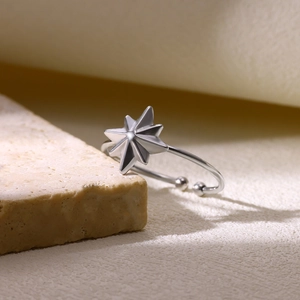 Détail d'une bague étoile ajustable sur un support en pierre beige texturée