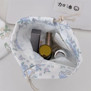 Detailed top view of a floral drawstring pouch holding lipstick and cosmetics