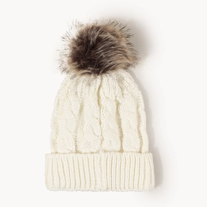 Close-up of knit winter hat in cream white featuring a fluffy faux fur pom-pom detail