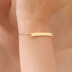 Detailed close-up of a minimalist 18K gold plated stainless steel curved bar bracelet on wrist