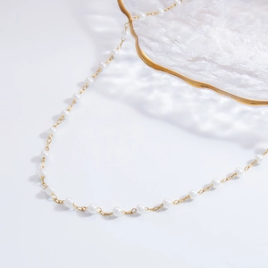 Detailed macro view of white pearls and golden stainless steel chain on glass plate