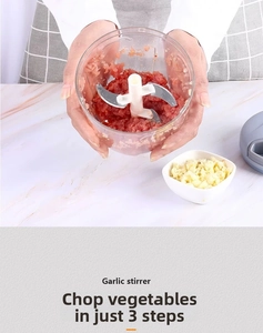 Manual food processor with stainless steel blades chopping meat in a transparent bowl