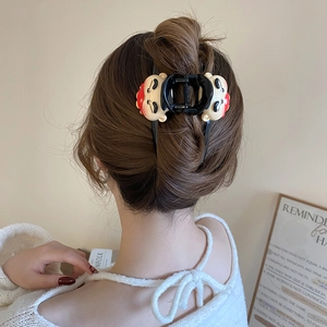 Detail shot of a creative black hair claw clip featuring red cartoon Caishen dolls