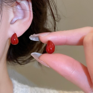 Close-up of elegant red teardrop earrings with a glossy translucent finish for women
