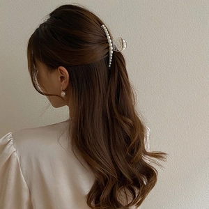 Detail of elegant white pearl hair claw clip and matching earrings on model