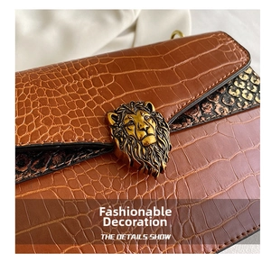 Detail of brown crocodile pattern shoulder bag featuring a gold lion head buckle
