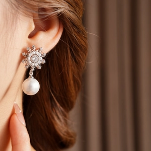 Gros plan de boucles d'oreilles flocon de neige en argent avec zircons et une perle ronde