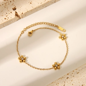Dettaglio macro di un bracciale floreale in acciaio inossidabile dorato con zirconi