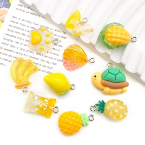 Flat lay of colorful resin charms including corn pineapple and butterfly with metal rings