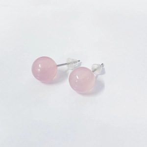 Close-up of pink quartz silver stud earrings with clear silicone backs on white surface