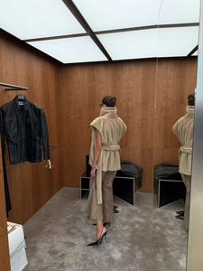 Détail d'un élégant gilet sans manches en fourrure beige avec ceinture et col montant chic