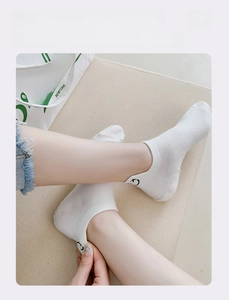 Detail of white cotton no-show socks featuring heel embroidery and breathable mesh texture