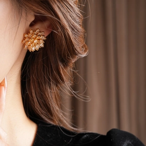Macro view of gold-plated flower stud earring with zircon on a model ear