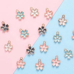 Colorful enamel cherry blossom pendants with rhinestones on a pink and blue background