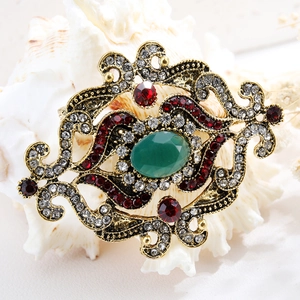 Vintage bronze brooch with green and red gemstones and clear rhinestones on dried flowers