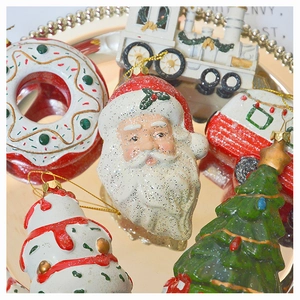 Detailed close-up of glittery Santa and doughnut Christmas ornaments in a gold tray