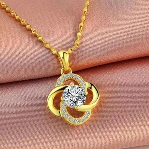 Macro shot of 18K gold plated clover pendant with a large center zircon on silk fabric