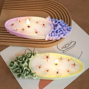 Detail of lit candle featuring intricate embossed floral motifs and elegant rose decor