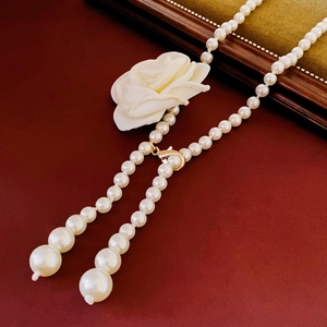 Détail du collier de perles blanches à double pompon avec fermoir mousqueton doré élégant