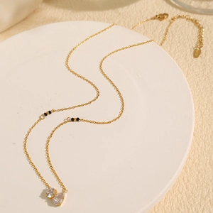Minimalist gold necklace with drop-shaped zircon pendant on white tray background