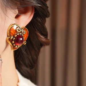 Close-up of vintage resin heart earrings with amber enamel and red gemstone