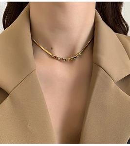 Golden snake chain necklace with colorful zircons worn on model with khaki blazer