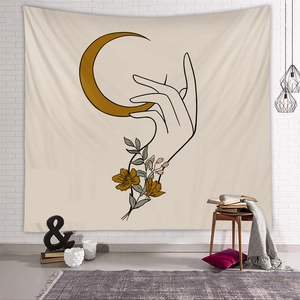 Dettaglio di un arazzo boho con mano e luna su una parete di mattoni bianchi
