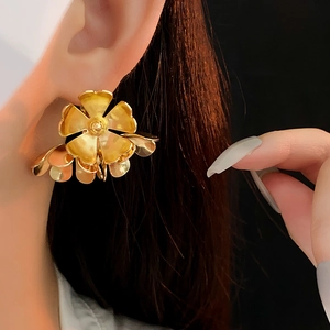 Close-up of golden multi-layer flower metal earrings worn by a model for fashion detail