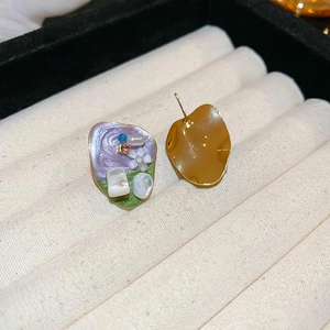 Detail of artistic floral studs with purple enamel, pearls and crystals on velvet
