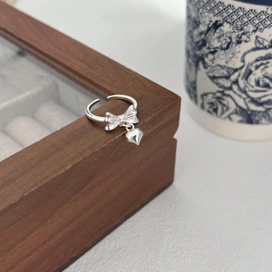 Minimalist S925 sterling silver bow ring with heart pendant on a wooden jewelry box