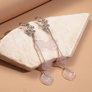 Elegant floral resin tassel earrings with silver chains on a minimalist stone display stand