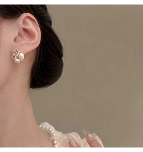 Macro shot of gold-plated earrings with pearls and zircon on model ear
