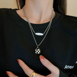 Double-layer silver necklace set with Dream pendant and checkerboard charm on black hoodie