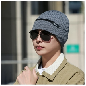 Detail of grey ribbed knit beanie with black stripes and branded side label