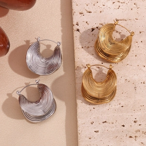 Detail of 18K gold and silver plated earrings with textured ribbing on silk and marble