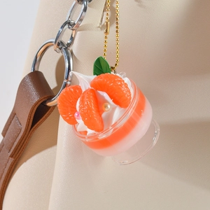 Miniature orange dessert sundae keychain pendant hanging on a white leather bag