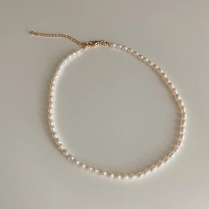 Detail view of small oval freshwater pearls with gold lobster clasp and extension chain