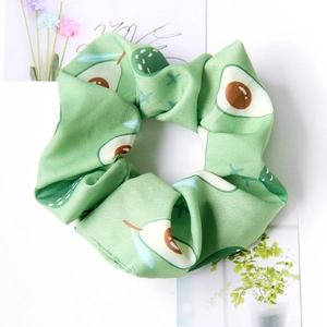 Detailed close-up of green satin scrunchie featuring cute avocado fruit patterns