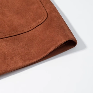 Detailed close-up showing the suede texture and double stitching of the brown jacket