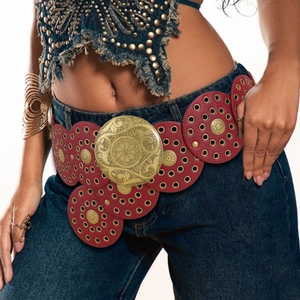 Detail of red leather belt with ornate gold buckle and circular metal eyelets