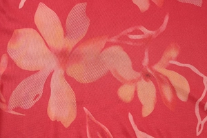 Gros plan sur un tissu en maille respirant avec motifs floraux rouges, orange et roses