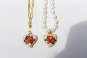 Detail of brass gold-plated enamel rose heart pendant with pearl and paperclip chains