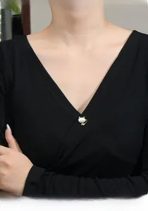 Close-up of a gold cat-shaped brooch with white stone on a black V-neck collar