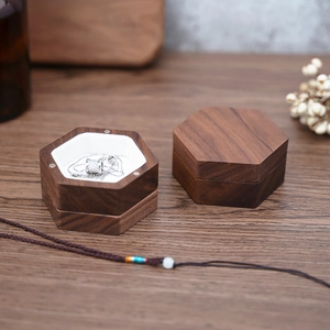 Detailed view of two hexagonal walnut jewelry boxes with white lining and silver necklace