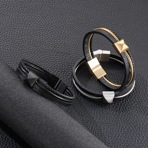 Détail d'un bracelet en cuir tressé multicouche avec des fermoirs magnétiques noir, or et argent