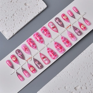 Detail of almond press-on nails with red lip, cherry, and ladybug designs in pink tones